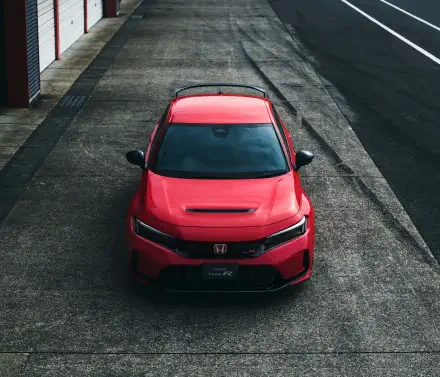 A striking red Honda Civic Type R parked on a textured surface, showcasing its sleek design and sporty features in vibrant 4K Ultra HD quality.