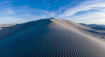 A stunning 4K Ultra HD image of sweeping sand dunes under a bright blue sky, showcasing intricate patterns on the sand and gentle ridges that lead to the horizon.
