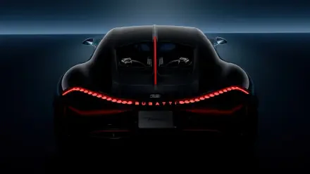 A sleek Bugatti Tourbillon captured in a striking 4K Ultra HD wallpaper, showcasing its dynamic rear design illuminated by captivating red lights against a dark background.