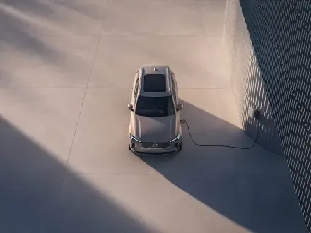 A top-down view of a Volvo XC90 Facelift, showcasing its sleek design and charging cable, set against a minimalist background. 4K Ultra HD quality enhances the details.