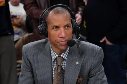 HD PC desktop wallpaper of Reggie Miller wearing a suit and headset, speaking during a broadcast with a blurred crowd in the background.