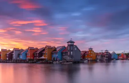 4K Ultra HD wallpaper of colorful houses along a waterfront in Groningen, Netherlands, under a vibrant sky at sunset.