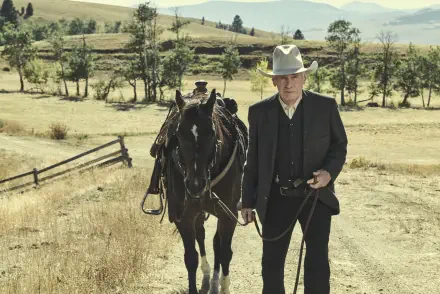 Harrison Ford as a cowboy in the TV show 1923, walking beside a black horse in a vast rural landscape, captured in 8K Ultra HD.