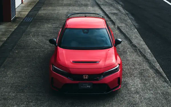 A striking red Honda Civic Type R parked on a textured surface, showcasing its sleek design and sporty features in vibrant 4K Ultra HD quality.