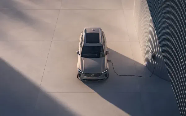 A top-down view of a Volvo XC90 Facelift, showcasing its sleek design and charging cable, set against a minimalist background. 4K Ultra HD quality enhances the details.