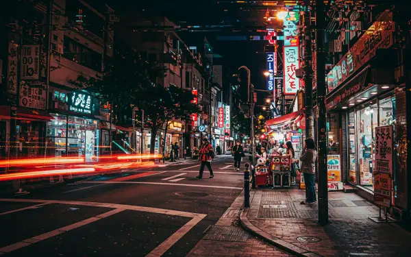 A vibrant street scene at night, featuring illuminated signs and bustling pedestrians, captured in stunning detail, showcasing urban life in 4K Ultra HD as a desktop wallpaper.