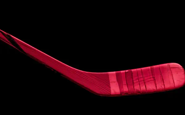 A vibrant red hockey stick isolated on a black background, captured in striking detail for a 4K Ultra HD PC desktop wallpaper.