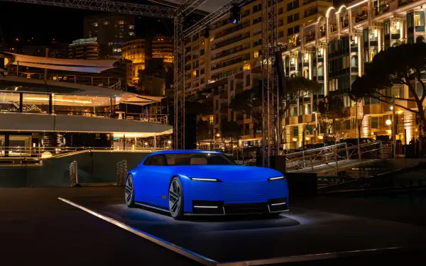 A blue Jaguar Type 00 parked at night in a brightly lit urban setting, captured in 8K Ultra HD as a PC desktop wallpaper and background.