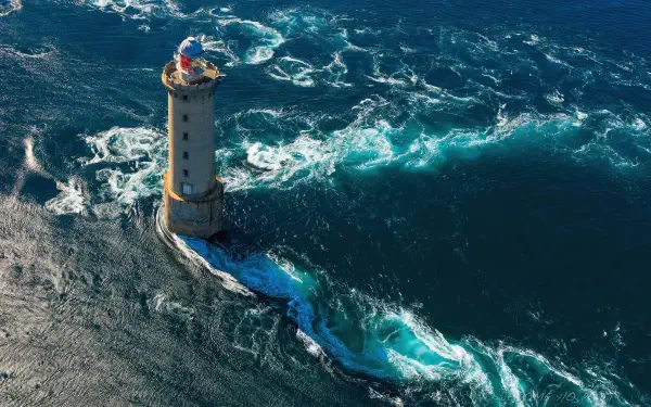 A 4K Ultra HD PC wallpaper featuring a solitary lighthouse standing firm amidst powerful ocean waves crashing around it.