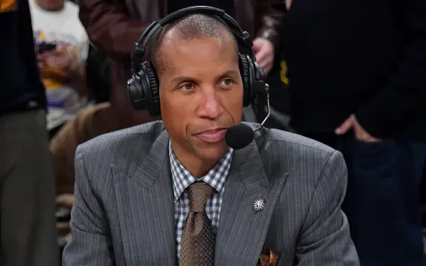 HD PC desktop wallpaper of Reggie Miller wearing a suit and headset, speaking during a broadcast with a blurred crowd in the background.