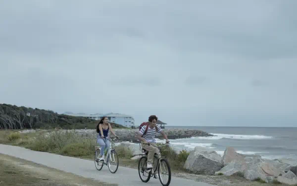 4K Ultra HD desktop wallpaper featuring a scene from the TV show The Summer I Turned Pretty, with two people biking along a coastal path under a cloudy sky.