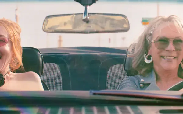 HD desktop wallpaper featuring Lindsay Lohan and Jamie Lee Curtis in a scene from the movie Freaky Friday, showing them smiling inside a car.