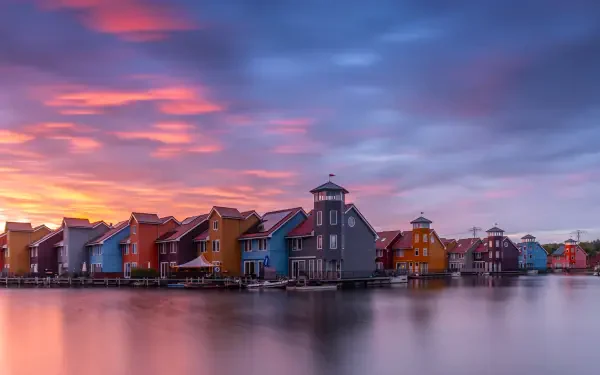 4K Ultra HD wallpaper of colorful houses along a waterfront in Groningen, Netherlands, under a vibrant sky at sunset.