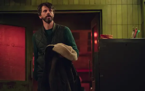 HD desktop wallpaper featuring Matthew Goode in a scene from the TV show Dept. Q, set in a dimly lit room with a moody atmosphere.