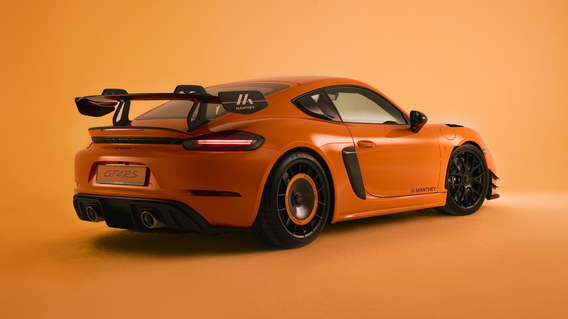 Orange Porsche 718 Cayman GT4, rear three-quarter view on a matching orange backdrop — 4K Ultra HD PC desktop wallpaper.