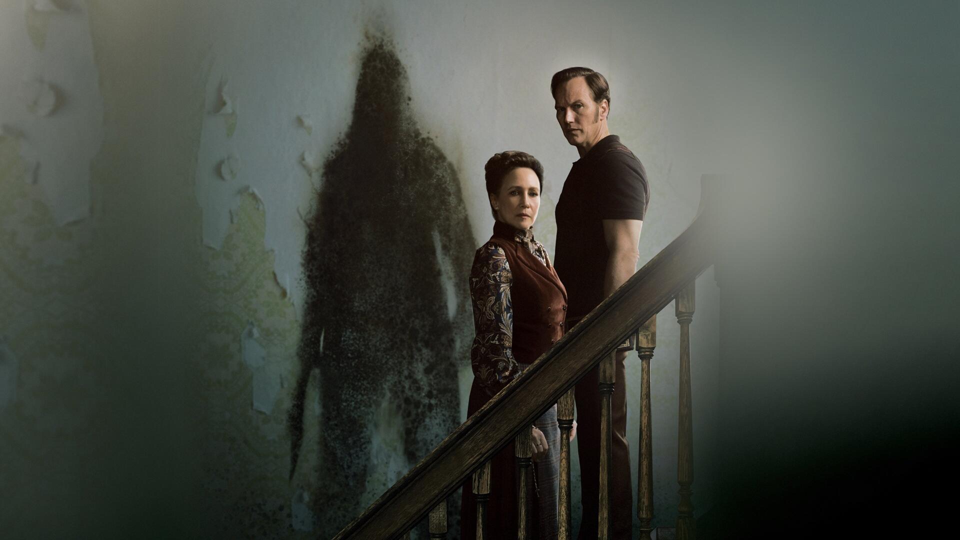 The Conjuring: Last Rites 4K Ultra HD PC desktop wallpaper and background — a couple on a dim staircase while a tall, shadowy apparition looms on the wall.