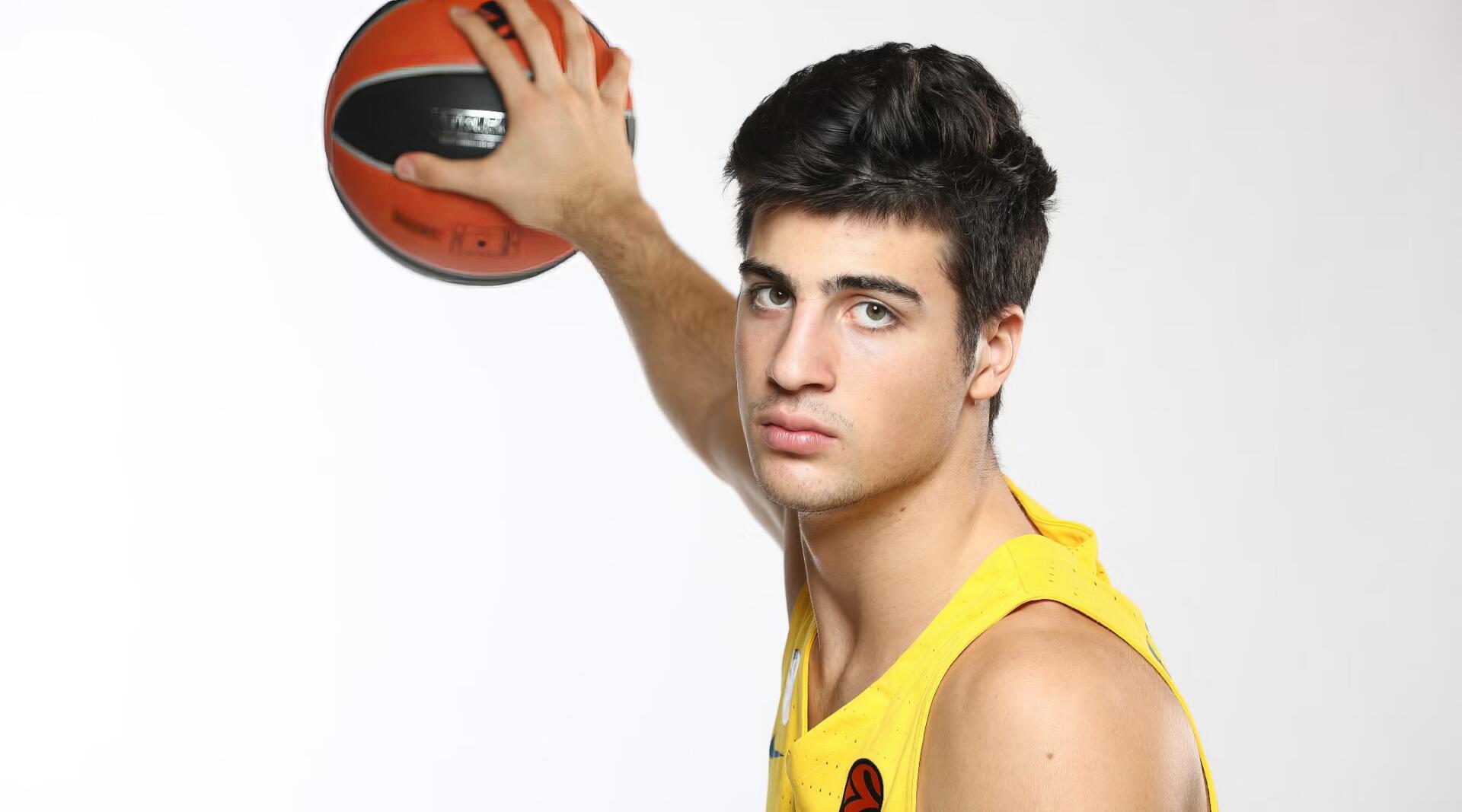 HD PC desktop wallpaper of a basketball player in a yellow jersey holding a ball overhead against a white background, close-up portrait with a focused expression.
