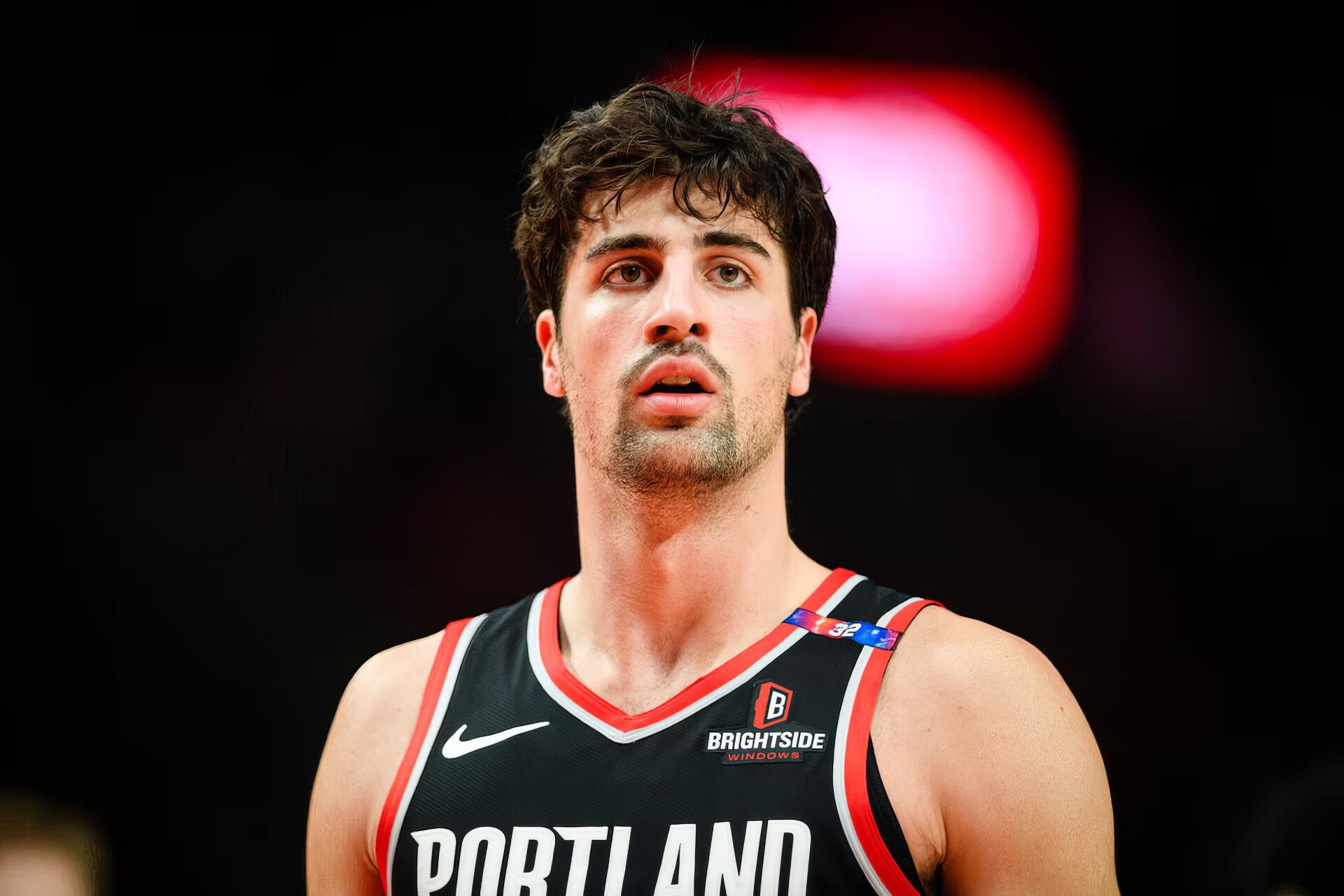 HD PC desktop wallpaper — close-up of a person wearing a Portland Trail Blazers jersey on an NBA basketball court, arena lights and crowd blurred in the background.