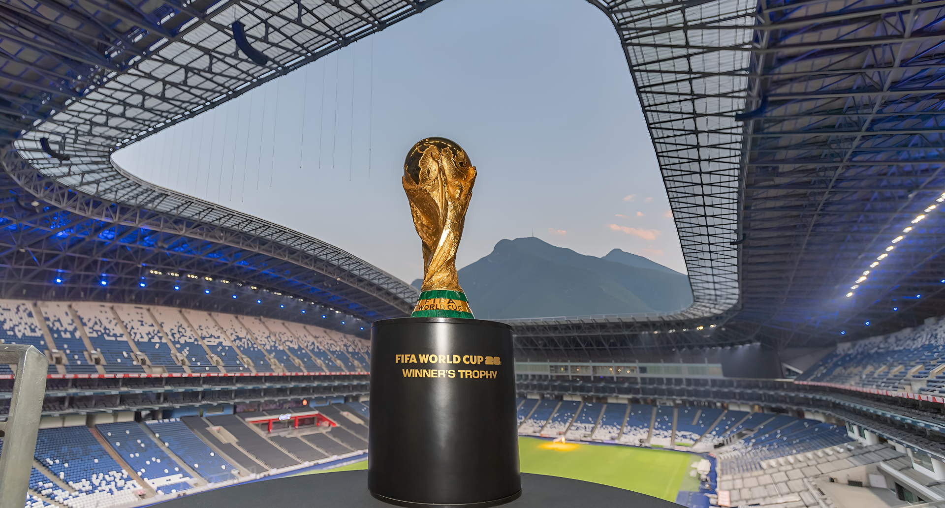 FIFA World Cup 2026 trophy on a pedestal at the center of a modern stadium at dusk — 2K Quad HD PC desktop wallpaper/background capturing World Cup atmosphere