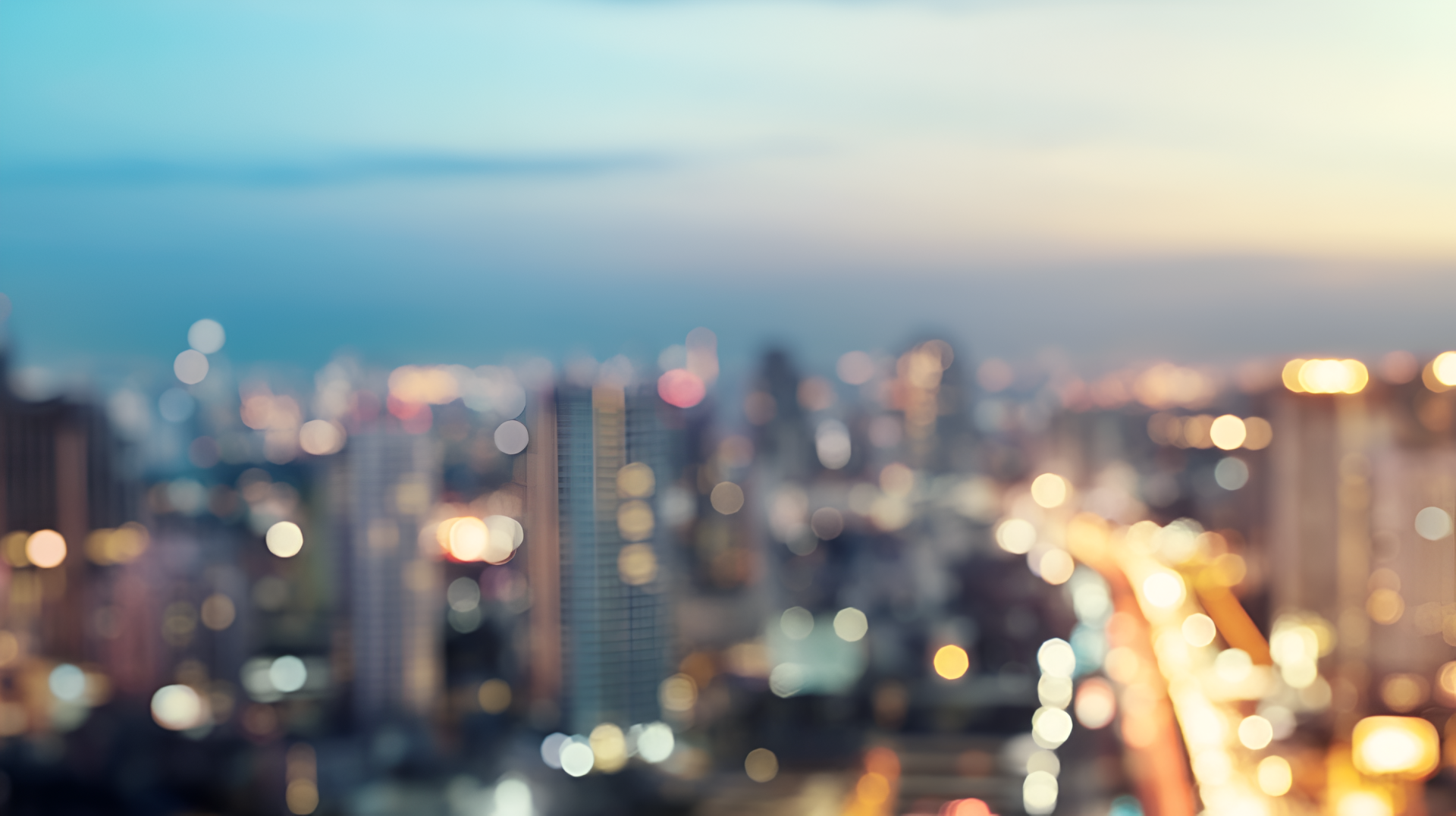 Blurred cityscape at dusk with glowing bokeh lights — 2K Quad HD PC desktop wallpaper and background.