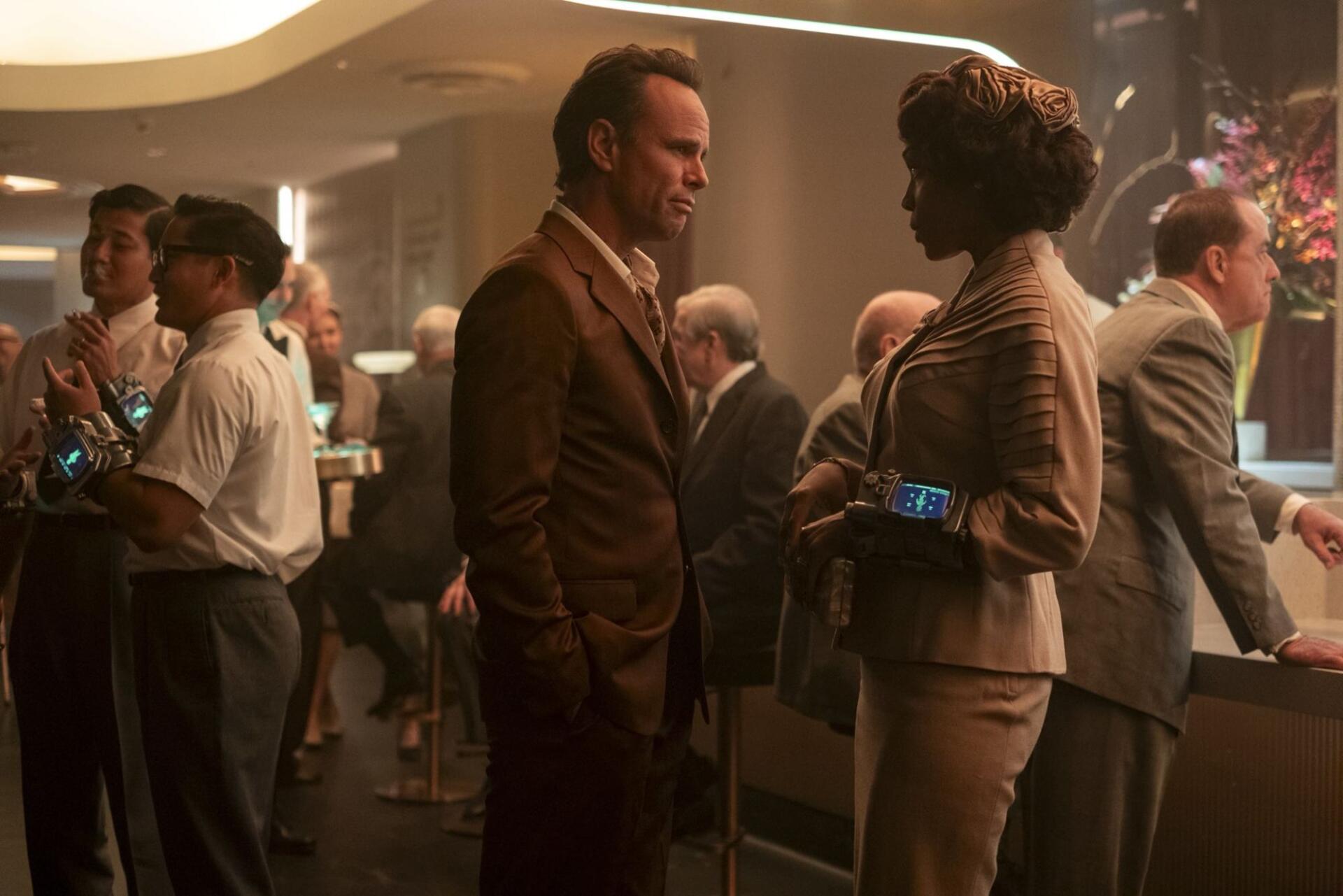 HD PC desktop wallpaper and background — Fallout (TV Show): two characters converse in a retro-futuristic casino lounge, warm cinematic lighting and patrons in the background.