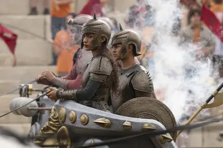 Bronze-armored chariot riders in a smoky stadium, action scene from the TV show Percy Jackson and the Olympians — HD PC desktop wallpaper/background.