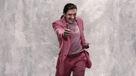 Street Fighter (2026) 2K Quad HD desktop wallpaper: man in a pink suit gives a thumbs-up while holding a hat, posed against a textured gray backdrop.