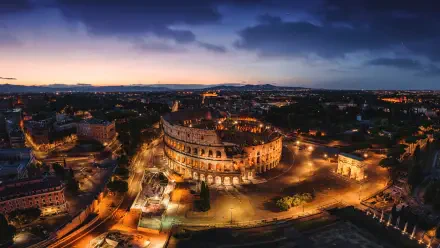 4K Ultra HD desktop wallpaper: aerial night cityscape of Rome, Italy, featuring the illuminated Colosseum and surrounding streets.