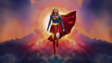Supergirl (2026) soaring above glowing clouds at sunrise, cape billowing and emblem shining — 5K Ultra HD PC desktop wallpaper and background.