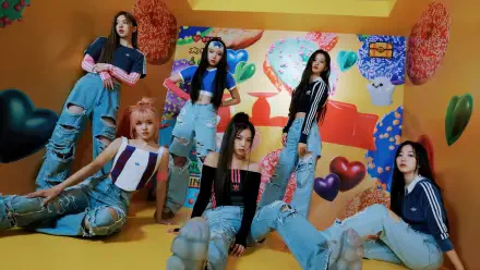 Six-member K-pop girl band posing in a colorful candy-themed set in ripped denim and crop tops — vibrant 4K Ultra HD PC desktop wallpaper background.