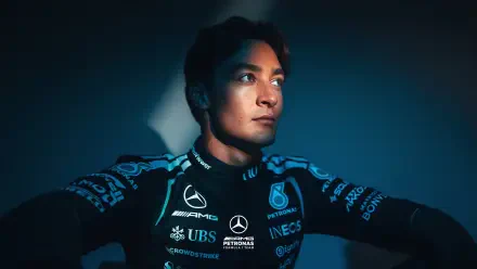 Moody portrait of a Mercedes AMG F1 driver in team race suit, gazing into light — 2K Quad HD PC desktop wallpaper/background with F1 racing theme.