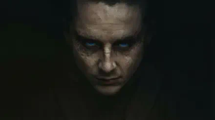 Moody close-up of a man's face with glowing blue eyes from Dune: Part Three; 2K Quad HD PC desktop wallpaper/background, shadowed sci‑fi portrait.