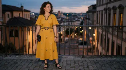 Woman in a flowing yellow dress on a cobblestone balcony overlooking a lit city at dusk — 5K Ultra HD PC desktop wallpaper and background.