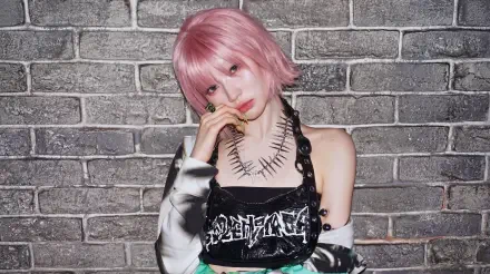 5K Ultra HD PC desktop wallpaper of a pink‑haired Japanese model in K‑pop drip style, wearing a leather harness top and spiked necklace, posing against a textured brick wall.