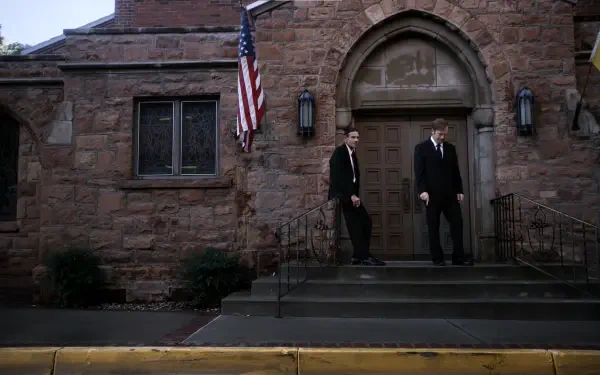 HD PC desktop wallpaper and background of TV show Better Call Saul featuring two suited men on stone church steps beneath an American flag.