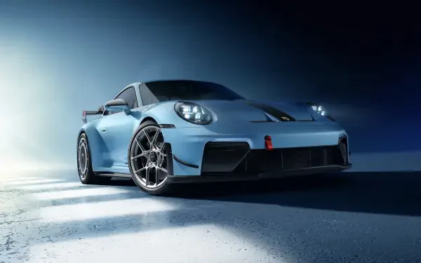 Blue Porsche 911 sports car on textured pavement under dramatic lighting — 8K Ultra HD PC desktop wallpaper/background.