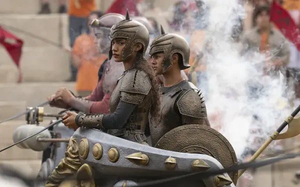 Bronze-armored chariot riders in a smoky stadium, action scene from the TV show Percy Jackson and the Olympians — HD PC desktop wallpaper/background.
