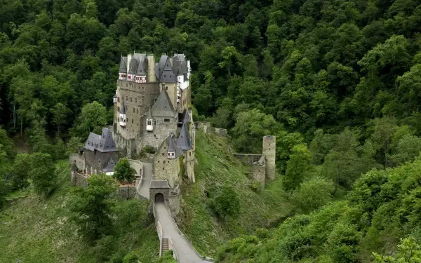 HD photography of Eltz Castle: a stone castle nestled among dense green trees, aerial view for an HD PC desktop wallpaper background.