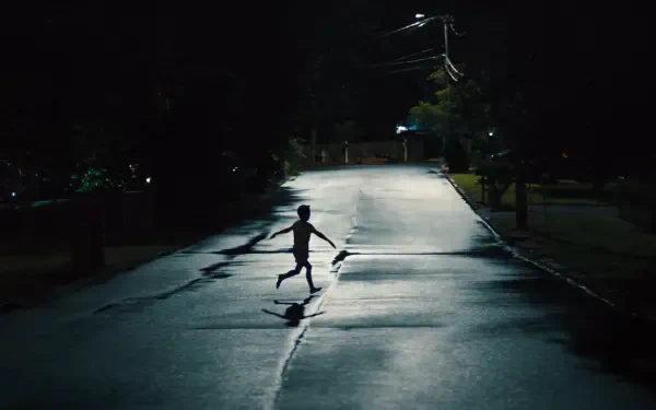 4K Ultra HD PC desktop wallpaper: lone silhouetted figure runs across a wet, dimly lit street at night, clutching a long object that looks like a weapon, casting a stretched shadow.