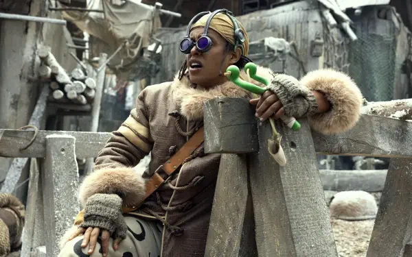 Live-action TV show image of Usopp from One Piece in a fur-lined outfit with goggles and slingshot, gritty dockside setting — 2K Quad HD PC desktop wallpaper/background.