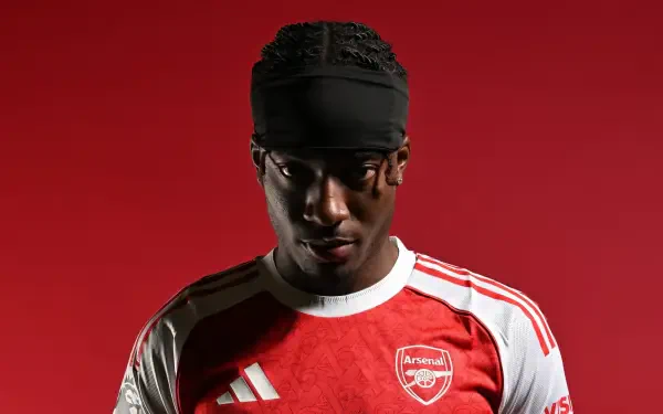 HD desktop wallpaper: Arsenal F.C. player in red home kit against a solid red background, close-up soccer portrait.