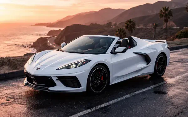 White Chevrolet Corvette convertible on a coastal road at sunset with palm trees and ocean cliffs — 5K Ultra HD PC Desktop Wallpaper and Background.