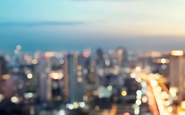 Blurred cityscape at dusk with glowing bokeh lights — 2K Quad HD PC desktop wallpaper and background.