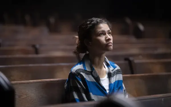 HD PC desktop wallpaper of a contemplative young actress from a TV drama, seated alone on wooden pews in dim light, gazing upward with a solemn expression.