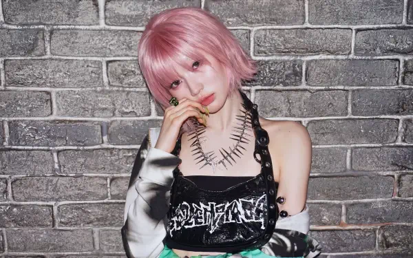 5K Ultra HD PC desktop wallpaper of a pink‑haired Japanese model in K‑pop drip style, wearing a leather harness top and spiked necklace, posing against a textured brick wall.