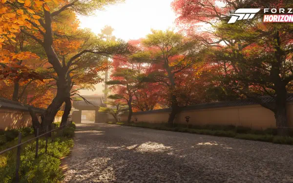 Forza Horizon 6 video game 4K Ultra HD PC desktop wallpaper: sunlit autumn avenue flanked by colorful maple trees, stone wall and a traditional gateway bathed in golden light.