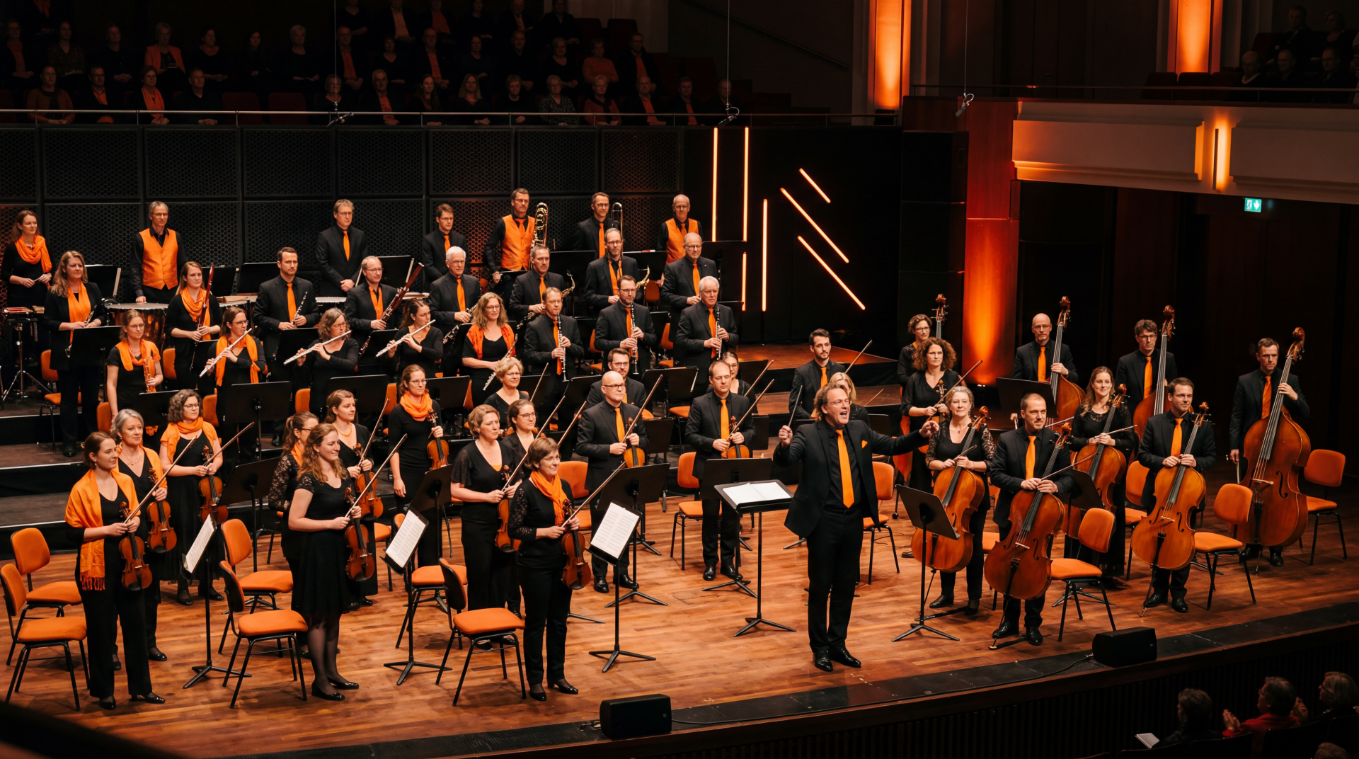 5K Ultra HD PC desktop wallpaper: full symphony orchestra onstage with conductor at center, musicians with strings, winds and brass under warm stage lighting.