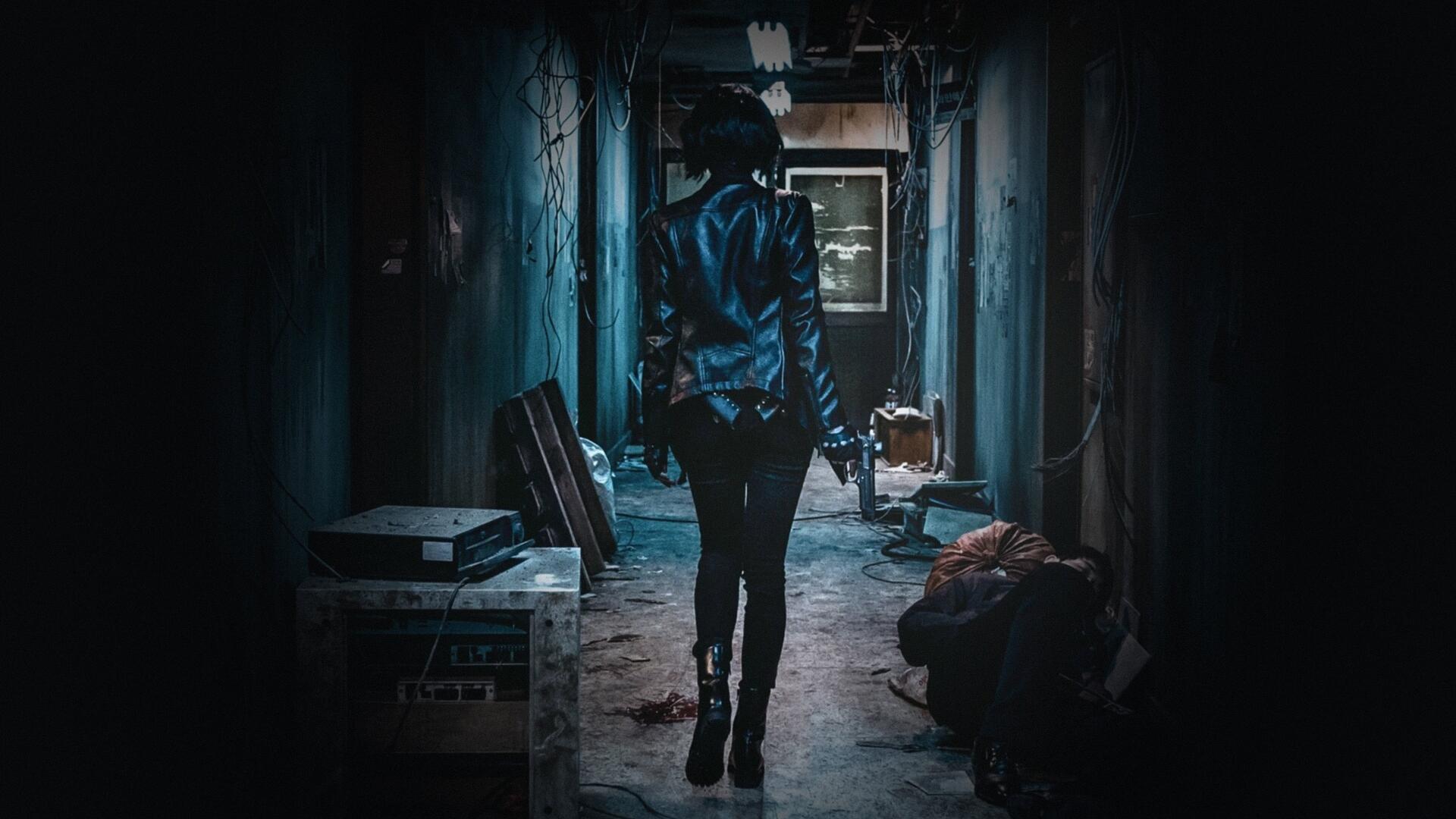 The Villainess — 4K Ultra HD PC wallpaper of a lone woman in a leather jacket walking down a dim, gritty corridor, pistol in hand toward a distant light.