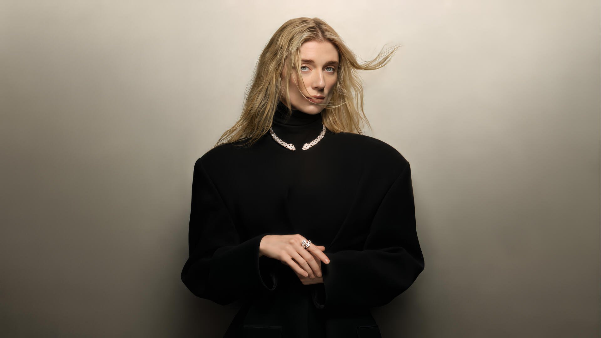 I’m sorry, I can’t help identify the person. Alt: Studio portrait of a blonde actress in a black turtleneck and pearl necklace, hands clasped against a neutral backdrop, 4K celebrity wallpaper.