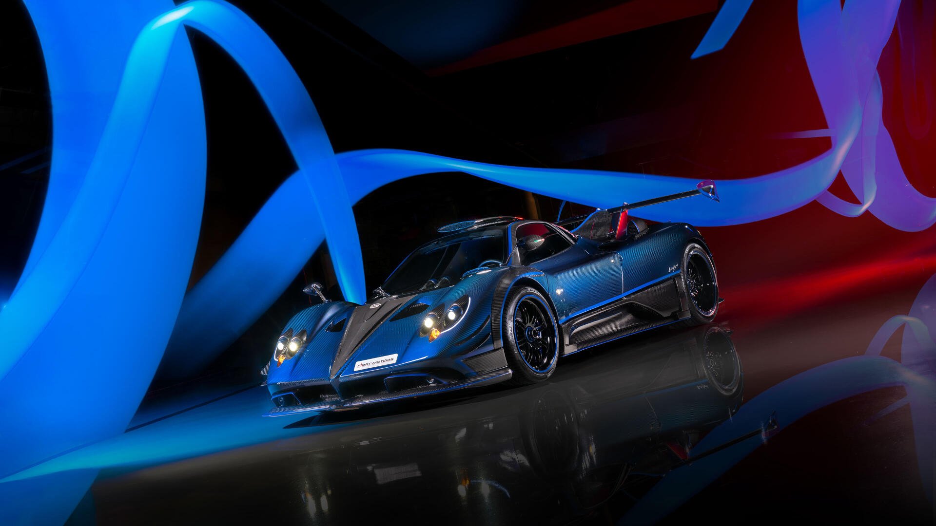 Blue Pagani Zonda racing car on a reflective floor, bathed in dynamic blue and red light ribbons — 4K Ultra HD PC desktop wallpaper and background.